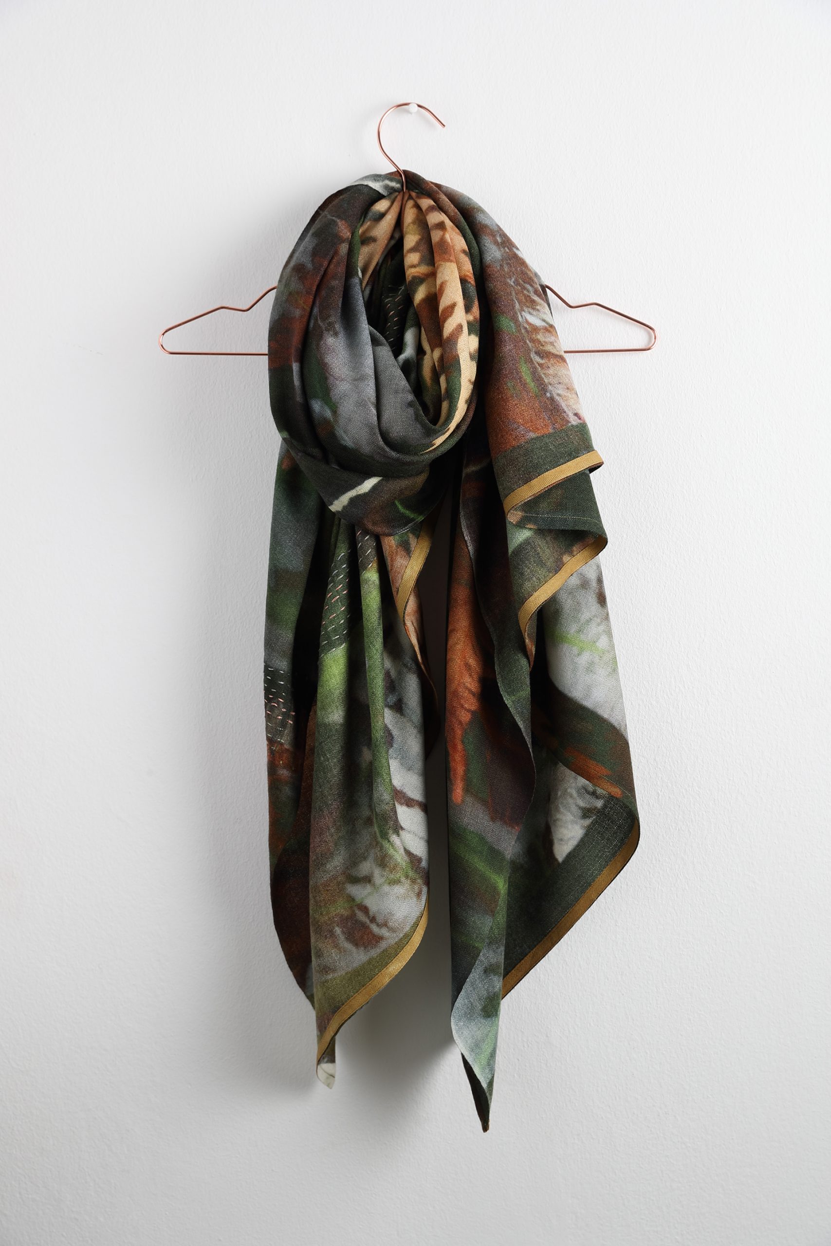 A beautiful Huckhl scarf draped around a hanger.