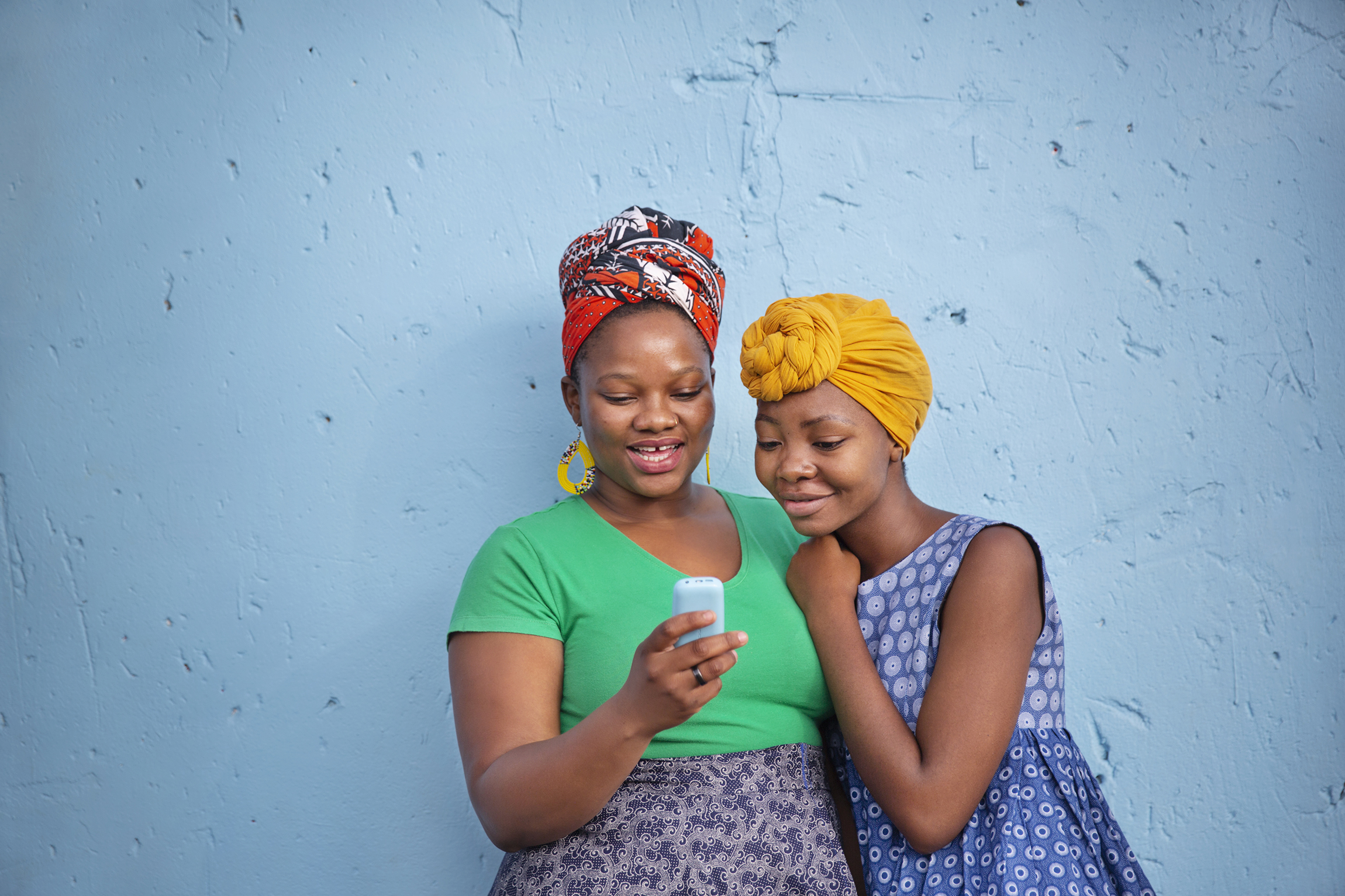 Two South African girl friends looking at a smartphone while smiling