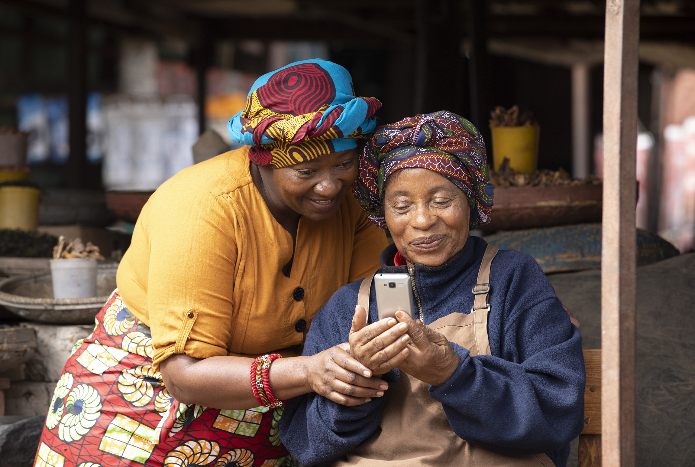 Two Zambian marketsellers looking at a cellphone