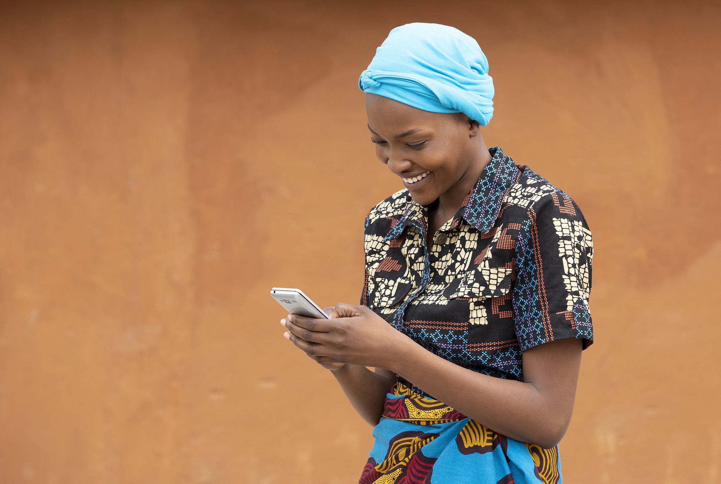 A young Zambian lady walking on the street looking at her phone and laughing